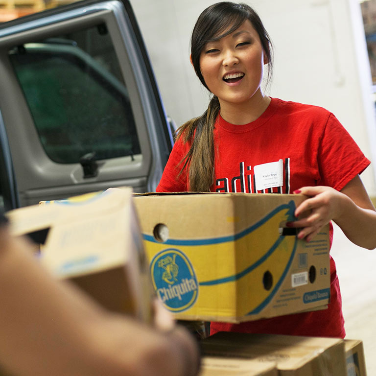 A student volunteer loads donated food into a truck.