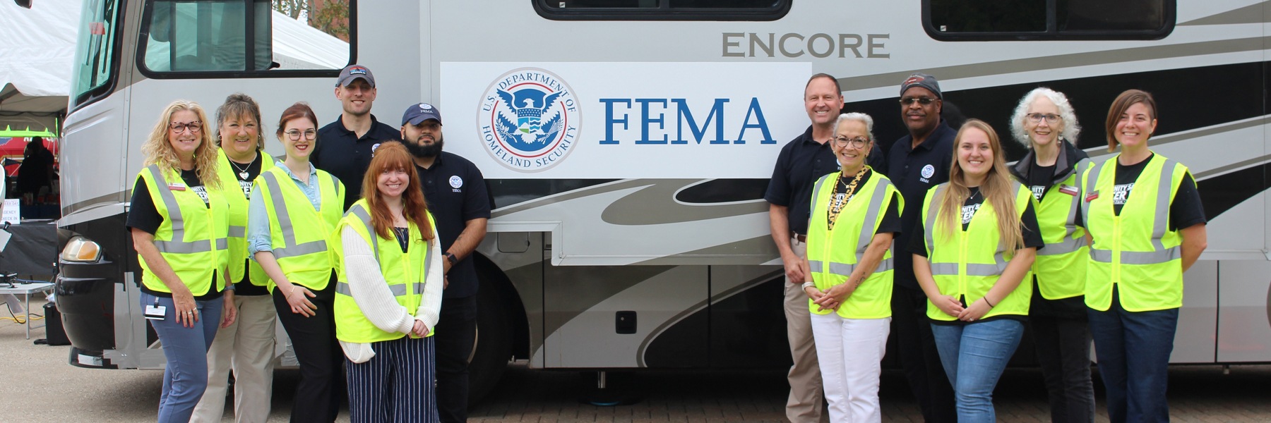 Group of people posing for a photo in front of the FEMA trailer.